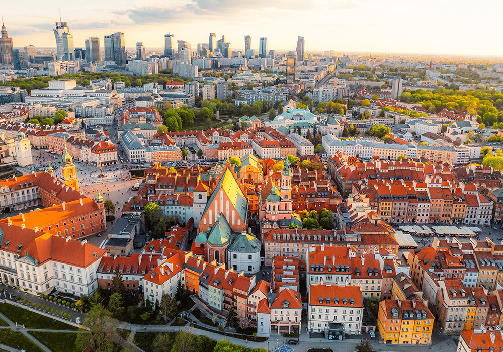 Ein Panorama von Warschau mit der Altstadt im Vordergrund. Im Hintergrund das moderne Zentrum von Warschau mit seinen gläsernen Wolkenkratzern.